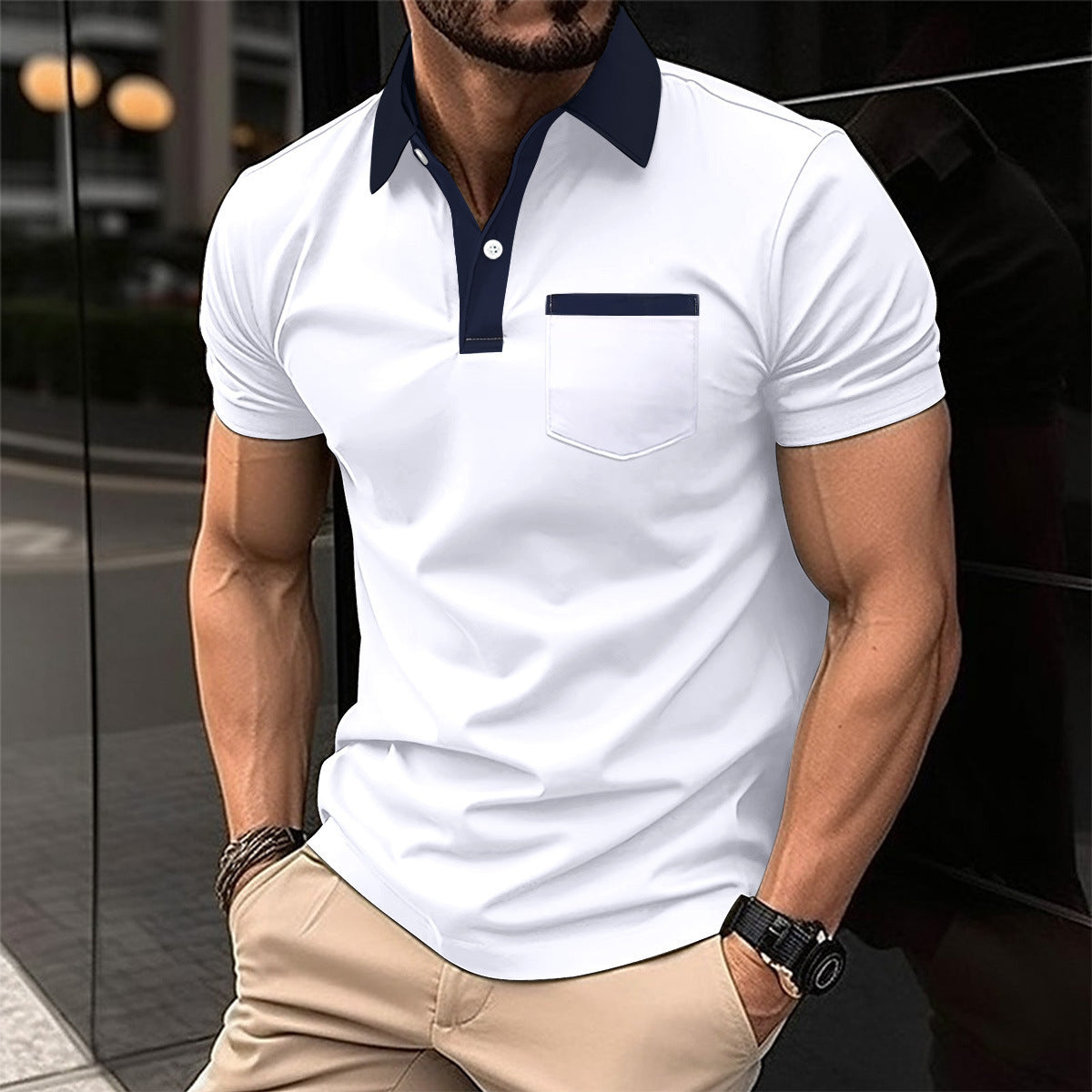 Man wearing a white polo shirt with navy accents and beige pants, standing against a reflective surface.
