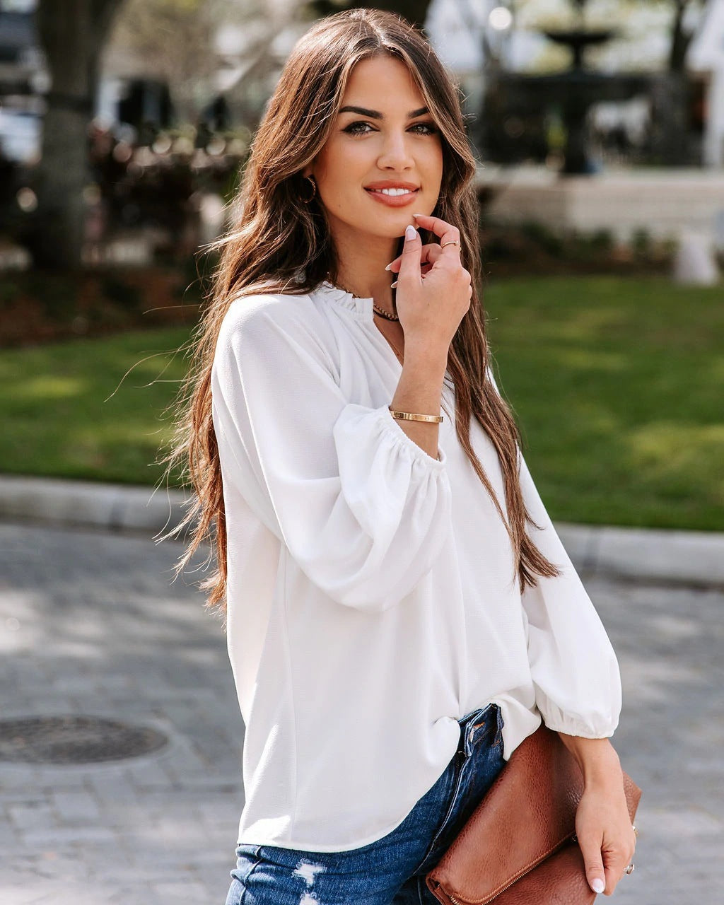 Woman wearing a white blouse and blue jeans outdoors