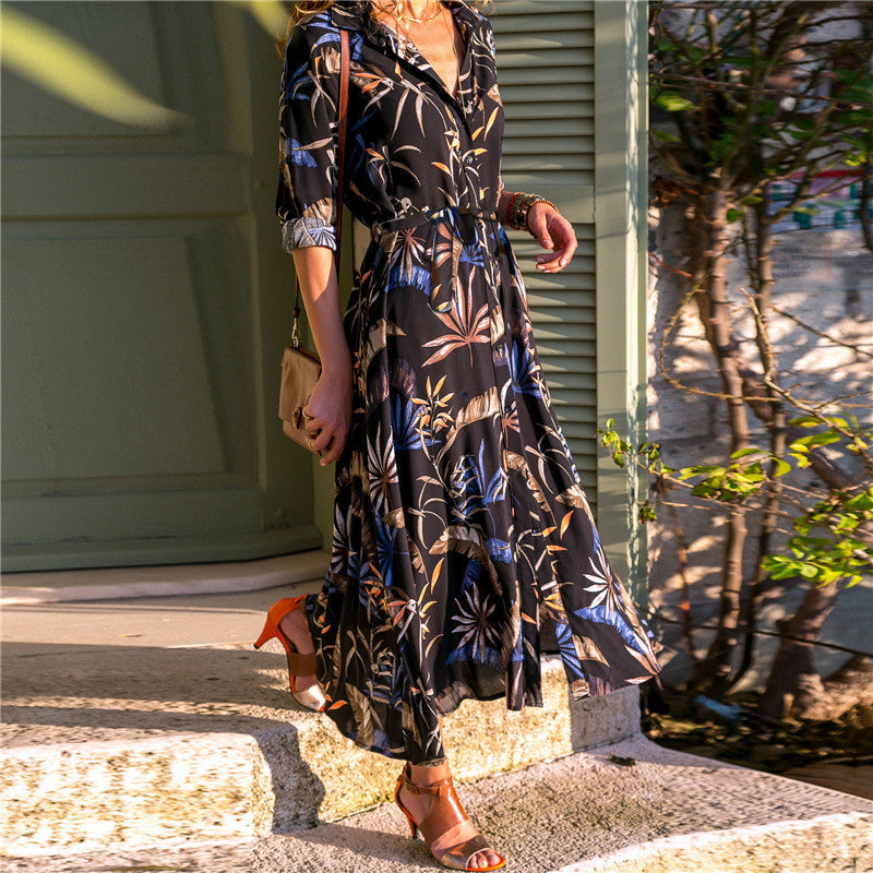 Woman in a floral dress standing on a street with trees and buildings in the background