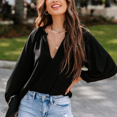 Woman wearing a black blouse and light blue jeans outdoors