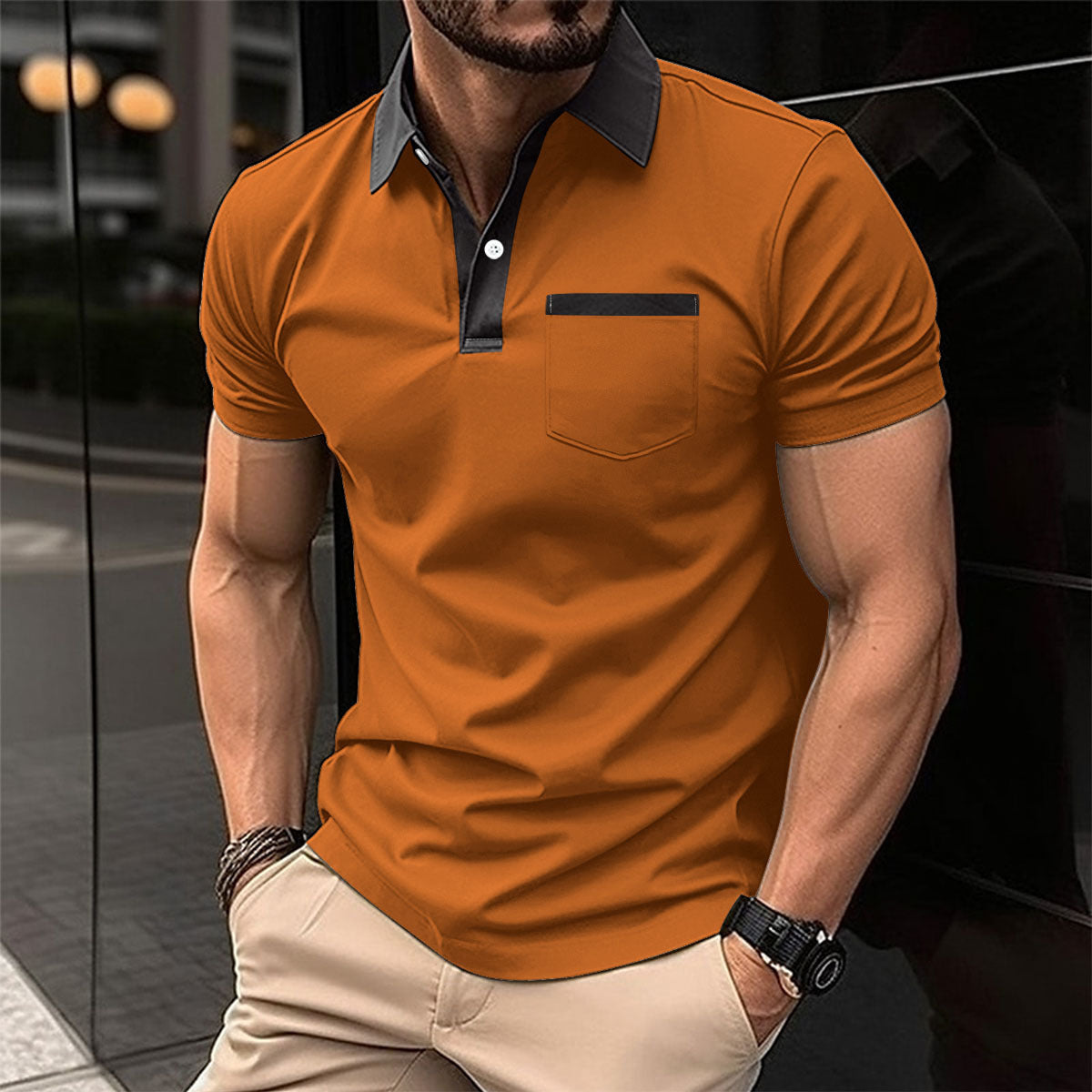 Man wearing an orange polo shirt with black collar and pocket trim, standing against a blurred background.