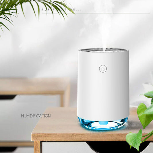 White humidifier with blue base on a wooden table, surrounded by green leaves.