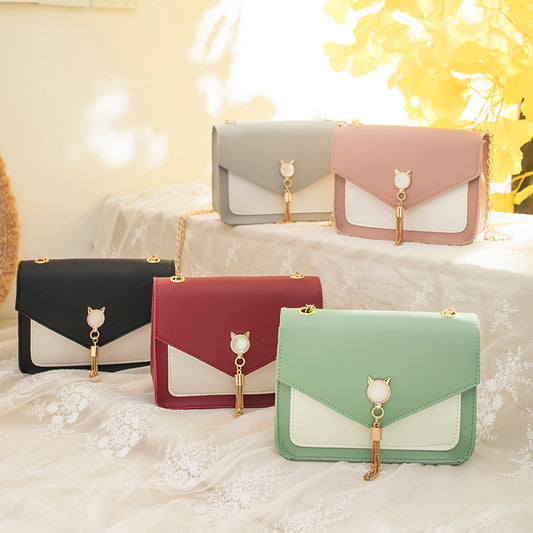Set of colorful handbags with cat-shaped handles on a soft surface.