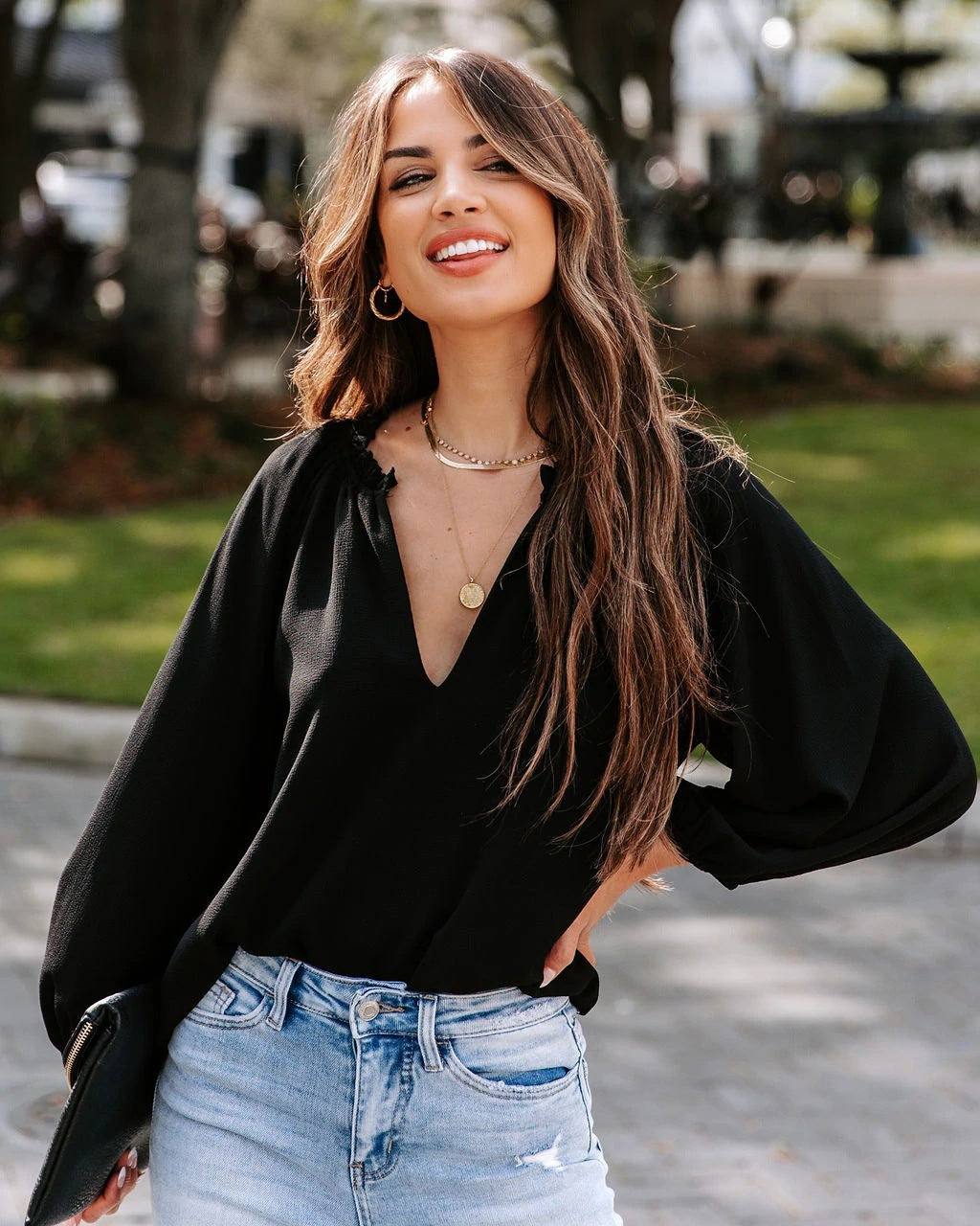 Woman wearing a black top and light blue jeans outdoors